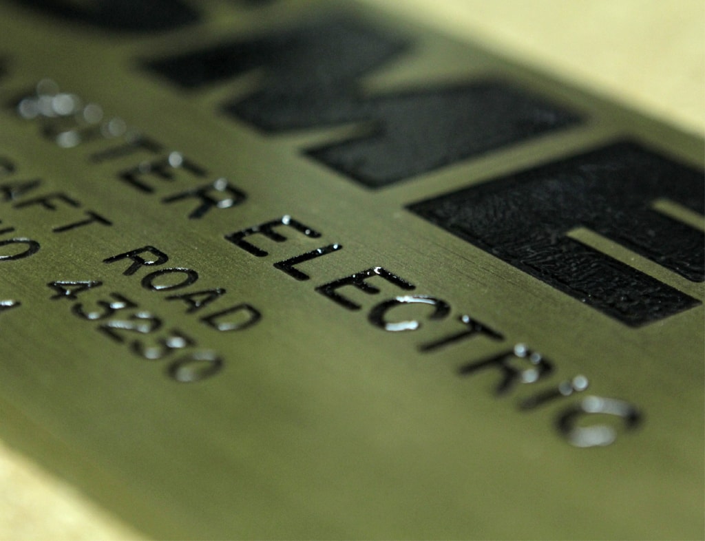 Close-up macro shot of a brass engraved nameplate — Electric Road address plate